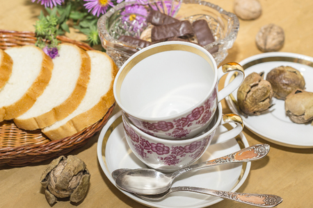 purple flowers, white bread and two cups on a wooden surfaceの写真素材