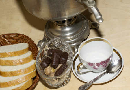 samovar on an old wooden table, bread and a tea cup with a spoonの写真素材