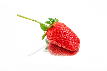 single fresh red strawberry in mirror surfaceの写真素材