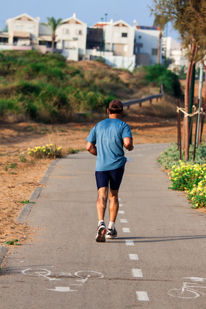 back view of a man running on a roadの写真素材