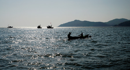 fishing boat  with  people and  ships. Wonderful   and  hard life. Backlight.  South India.の写真素材