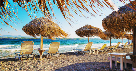 thatched roof umbrellas and lounge chairs by the seaの写真素材