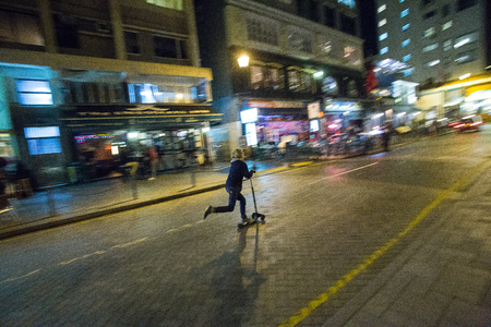 Unrecognizable  girl moves on a scooter. HongKong  . Eveningの写真素材
