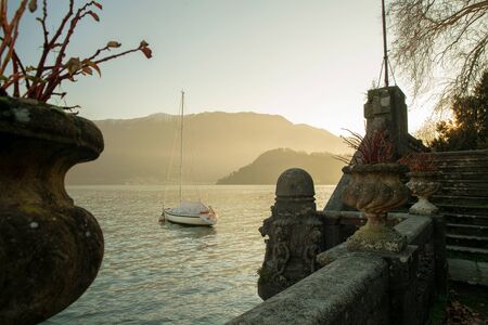 Majestic view on ancient Villa  and sailboat  near on Lake Como.  Soon sunsetの写真素材