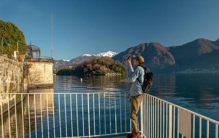 Chinese tourist makes a video of beautiful landscapes on Lake Como. Beautiful sunny  dayの写真素材