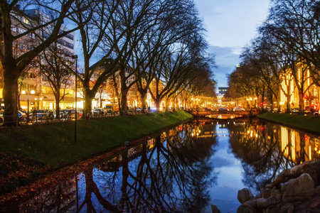 Awe Konigsallee with pond in the center with expansive boutique- yellow street lights, illuminated cityの写真素材