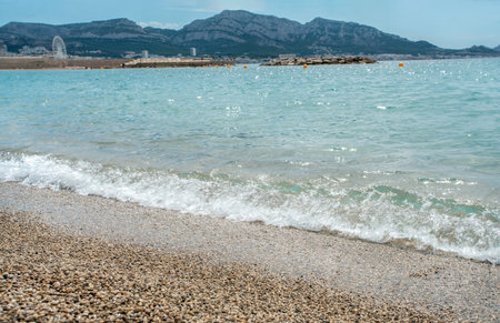Fantastic mild waves with shiny sunbeams reflecting in water - French Riviera for relaxation and recreation in suburb of Marseiile (or Antibes or Nice, or Cannes or Monaco, or Toulon). Very small pebbles comfortable for walking to water to swimm. Zen-like.の写真素材