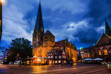 Church of OUR Ladyand City hall (Rathaus) in Bremen, amazing twilighs. Unrecognizable person walking in Ukrainian flag colors (blue and yellow)- blurred motion people.の写真素材