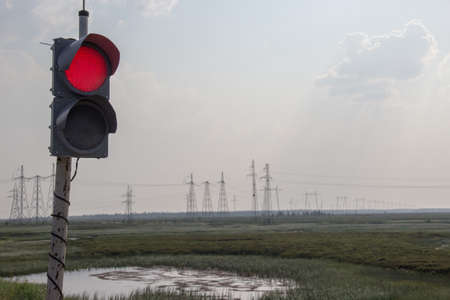Red traffic light on the background of power lines