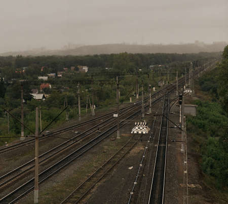 Railroad tracks in cloudy weather against the background of a rainy cityの写真素材