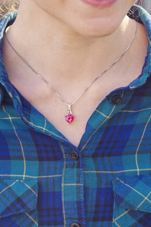 Detal of woman wearing a luxury heart shape ruby pendantの写真素材