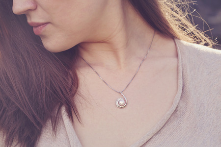 Detal of woman wearing a luxury pearl pendantの写真素材