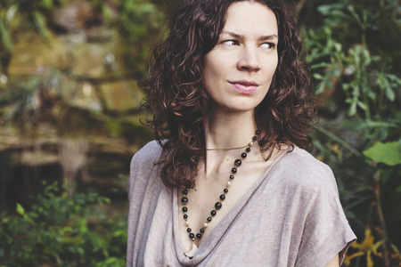 Beautiful woman with curly brown hair in the exotic green gardenの写真素材