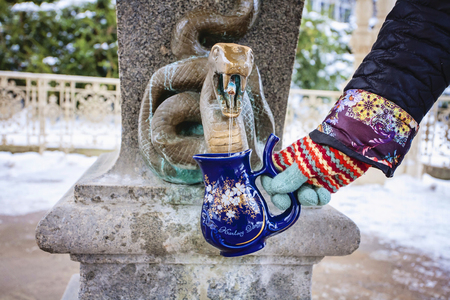 Hand filling a cup with therapeutic mineral water at a natural hot spring in Karlovy Vary during winter time, Czech Republicのeditorial素材