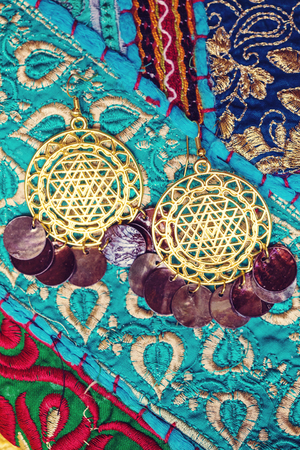 golden plated earrings on blue decorative textile