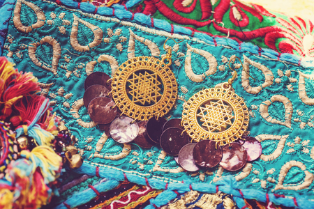 golden plated earrings on blue decorative textileの写真素材