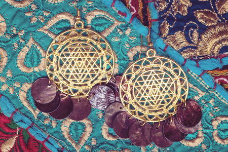 golden plated earrings on blue decorative textileの写真素材