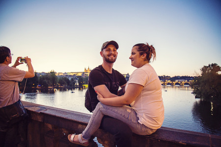 Prague, Czech republic, April 30, 2018: Happy couple sitting at the bridge with Prague Castle backgroundのeditorial素材