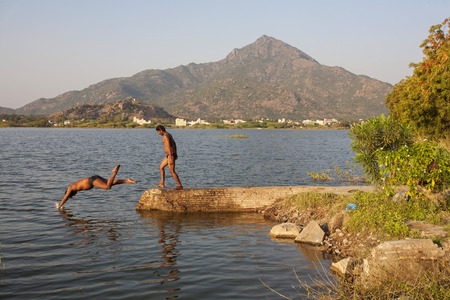 Tiruvannamalai / Tamil Nadu / India, February 1, 2018: Young Indians taking bath in the lake next to Arunachala mountain のeditorial素材