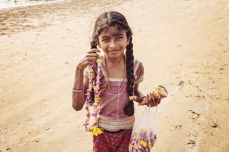 Gokarna, Karnataka, India, January 8, 2018: Little girl selling natural blossom necklaces on the Kudli Beachのeditorial素材