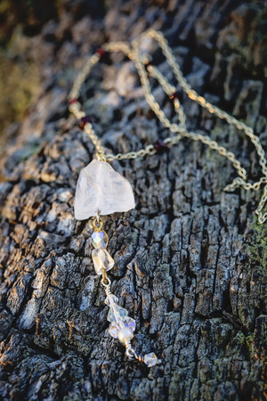Antique chain natural crystal quartz pendant necklace on wooden backgroundの写真素材