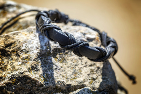 Black male bracelet on rocky background