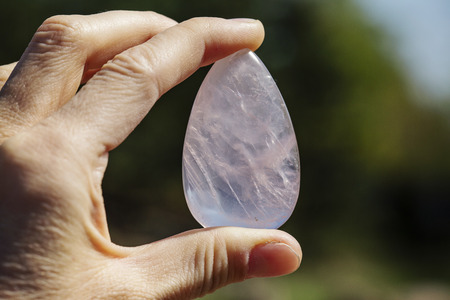 Female hand holding processed gemstone Rose quartz