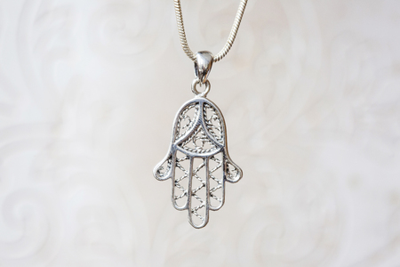 Silver hamsa Fatima hand pendant on natural white backgroundの写真素材