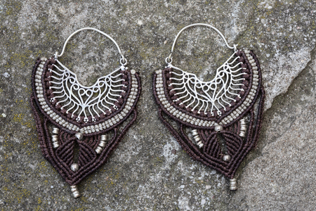 Metal macrame earrings on rocky backgroundの写真素材