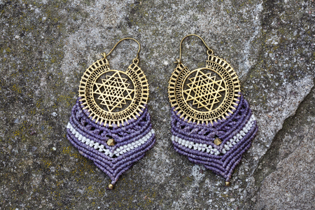 Metal macrame earrings on rocky backgroundの写真素材