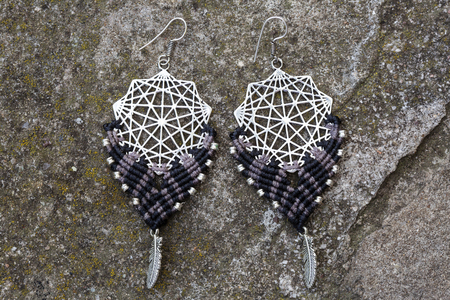 Metal macrame earrings on rocky background