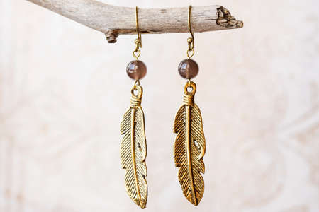 Brass metal earring on natural neutral backgroundの写真素材