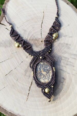 Macrame necklace with natural mineral gemstone on wooden background