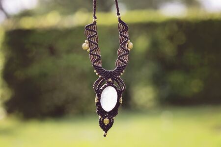 Macrame boho style necklace on green outdoor blury background