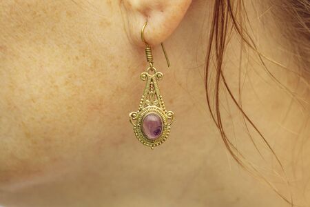 woman wearing brass metal earring with Amethyst mineral gemstoneの写真素材