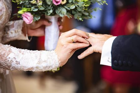 Bride hand putting a wedding ring to her groom finger