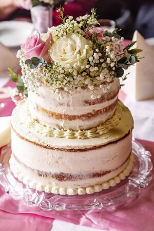 Wedding cake placed on a table with real flowers