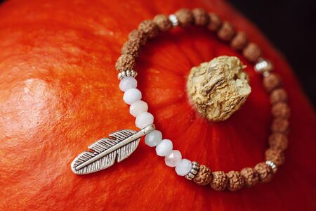 Tiny mineral stone bracelet on string placed on orange hokaido pumpkinの写真素材