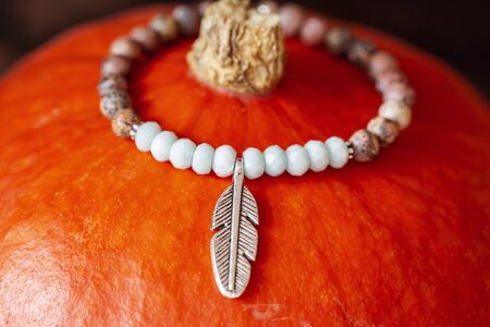 Tiny mineral stone bracelet on string placed on orange hokaido pumpkinの写真素材