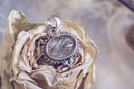 Sterling silver crystal quartz rutile mineral stone pendant on rose backgroundの写真素材