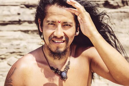 Outdoor portrait of fashionable long hair young man with bindi and jewelryの写真素材