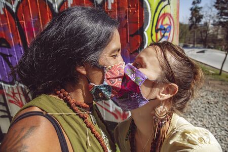 Outdoor portrait of couple wearing protective face masks and kissing