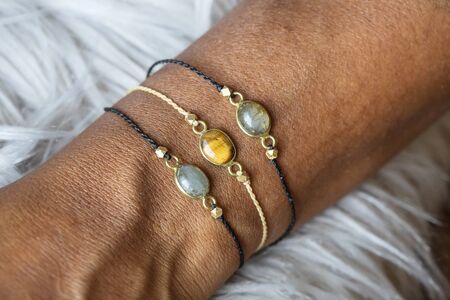 Closeup of a hand wearing tiny elegant mineral stone bracelets on fury background の写真素材