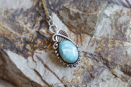Brass pendant with natural larymar gemstone on rocky backgroundの写真素材