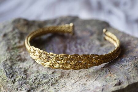 Brass metal wire elegant bracelet on rocky backgroundの写真素材