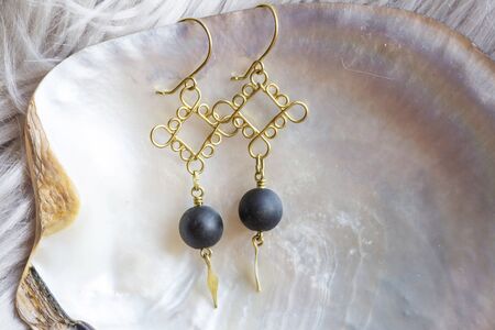 Tiny elegant female earrings with mineral stone beads on natural white shell backgroundの写真素材