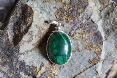 Beautiful malachite mineral stone pendant on rocky backgroundの写真素材