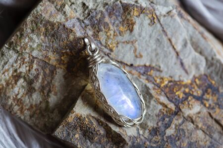 Beautiful mineral moon stone pendant on rocky background
