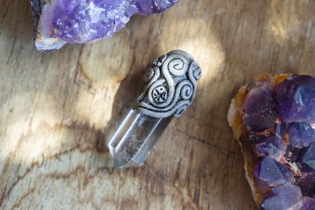 Beautiful crystal quartz gemstone pendant on wooden backround with amethyst druses 