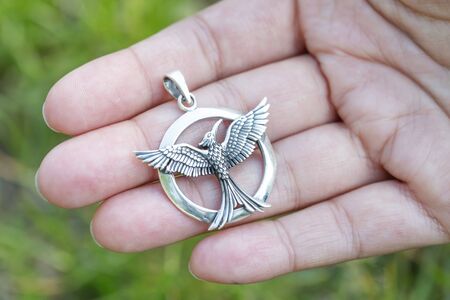 Sterling silver pendant in the shape of a bird on female handの写真素材